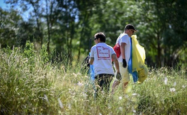 Voluntaria recogiendo basura en un entorno natural.