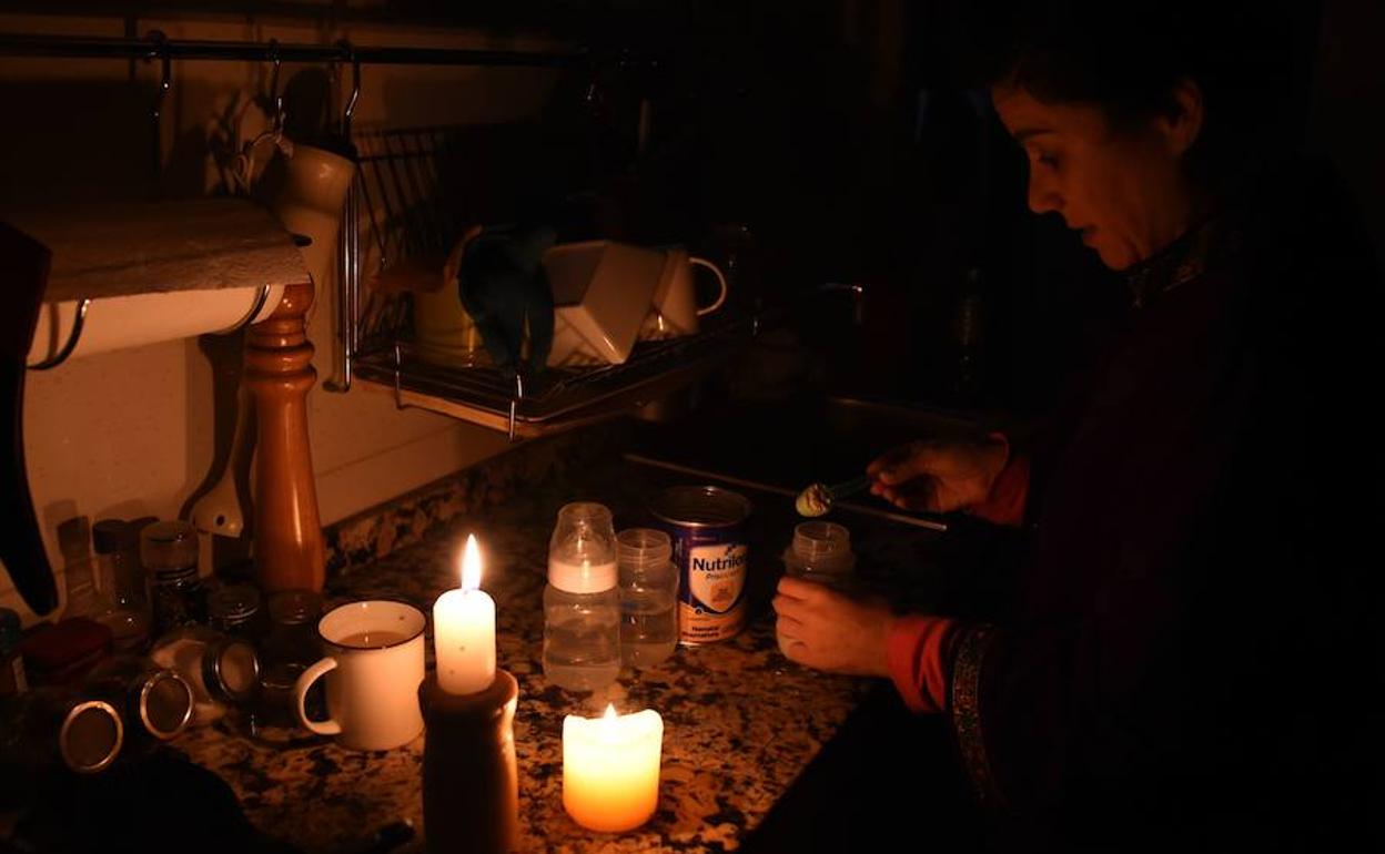 Una mujer prepara botellas de leche con velas en su casa en Montevideo.