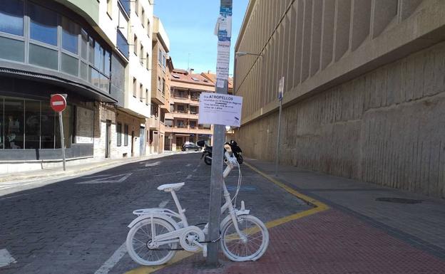 Bicicleta pintada de blanco atada a una farola en la Plaza de la Universidad. 