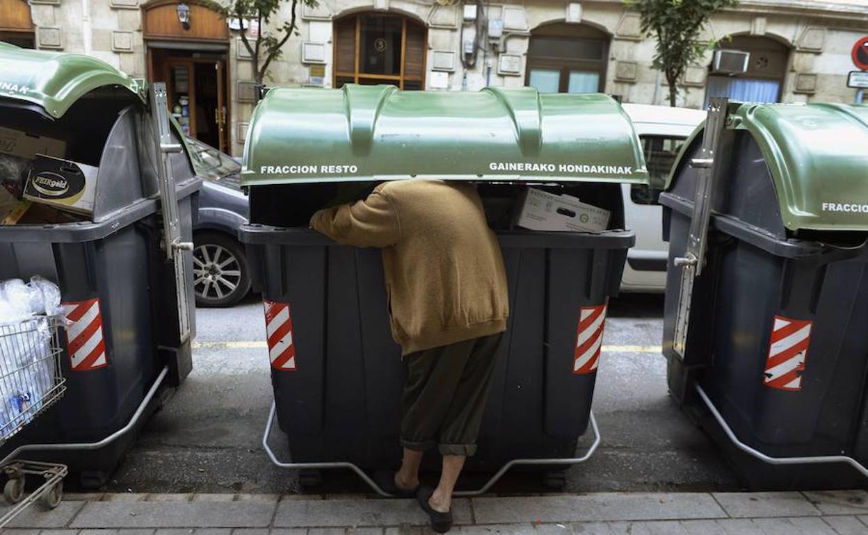 Un hombre busca comida en un contenedor de basura en Bilbao.