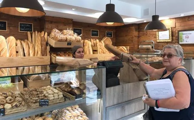 Una mujer compra pan en una tahona. 