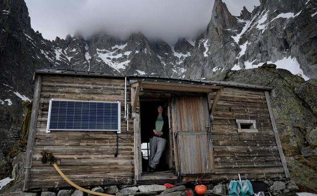 Imagen principal - La joven posa en el umbral de la puerta del albergue, en el que recibe a los excursionistas durante los meses de verano. La guardesa juega con su hijo Armand en la cocina del refugio, donde prepara el desayuno y la cena para los alpinistas que paran allí. El refugio no tiene electricidad ni agua corriente. El baño se encuentra fuera. 