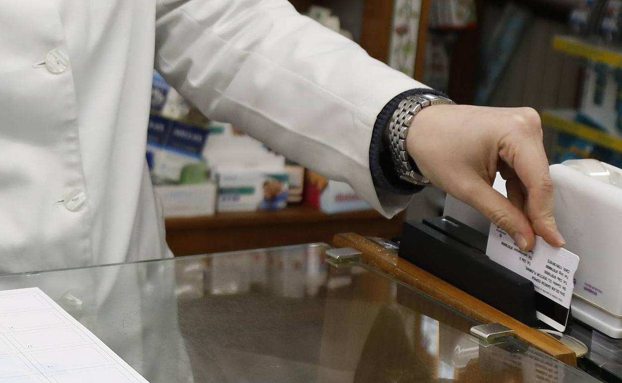 Una farmacéutica pasa la receta electrónica por el lector. 