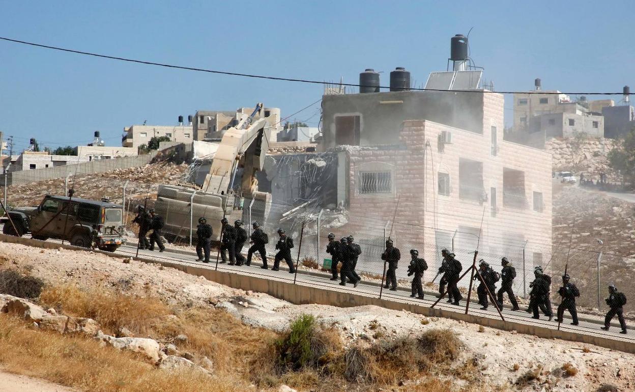 Las fuerzas de seguridad israelies toman posiciones, mientras que una mática tira una de las viviendas.