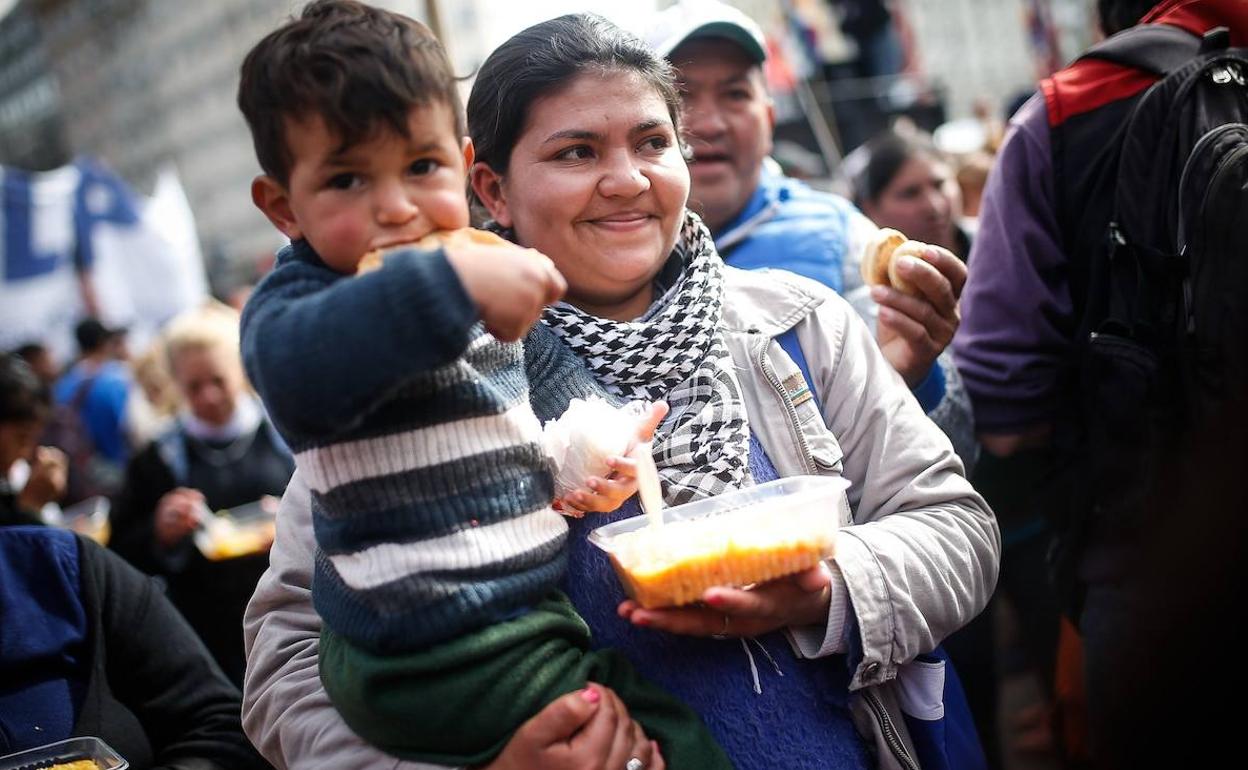 Una mujer y su hijo reciben comida este jueves durante una movilización contra el gobierno de Mauricio Macri por la crisis económica en Buenos Aires. 