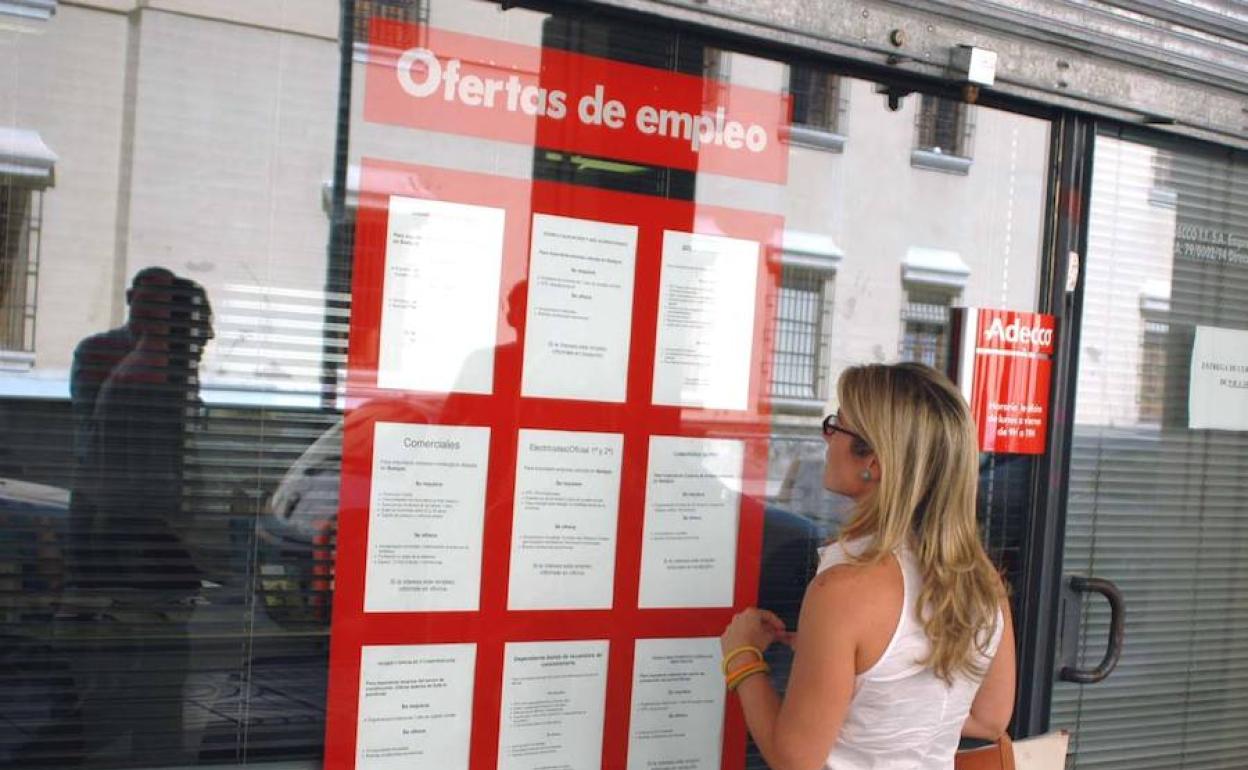 Una joven mira ofertas de empleo en un escaparate.