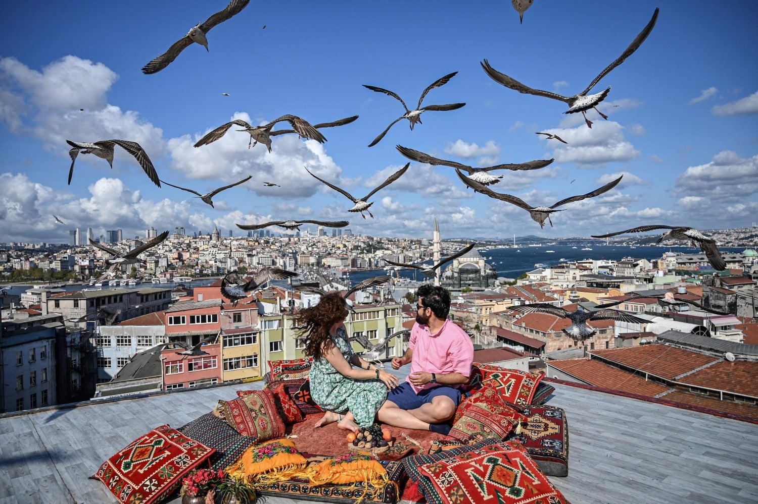 Una pareja se sienta en la terraza de un café en Estambul mientras las gaviotas vuelan sobre ellos