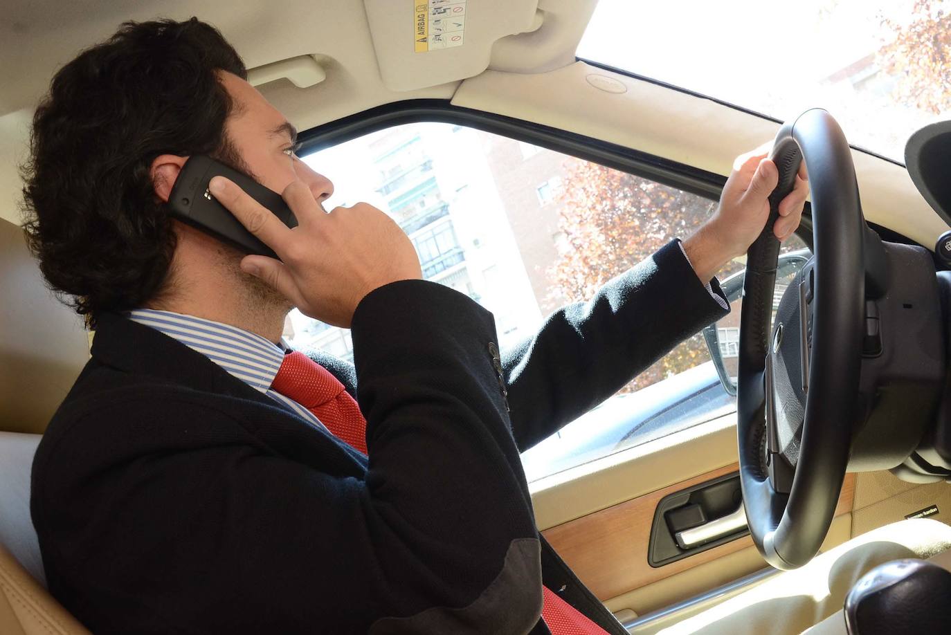 Un hombre habla por el teléfono móvil en el coche mientras conduce.