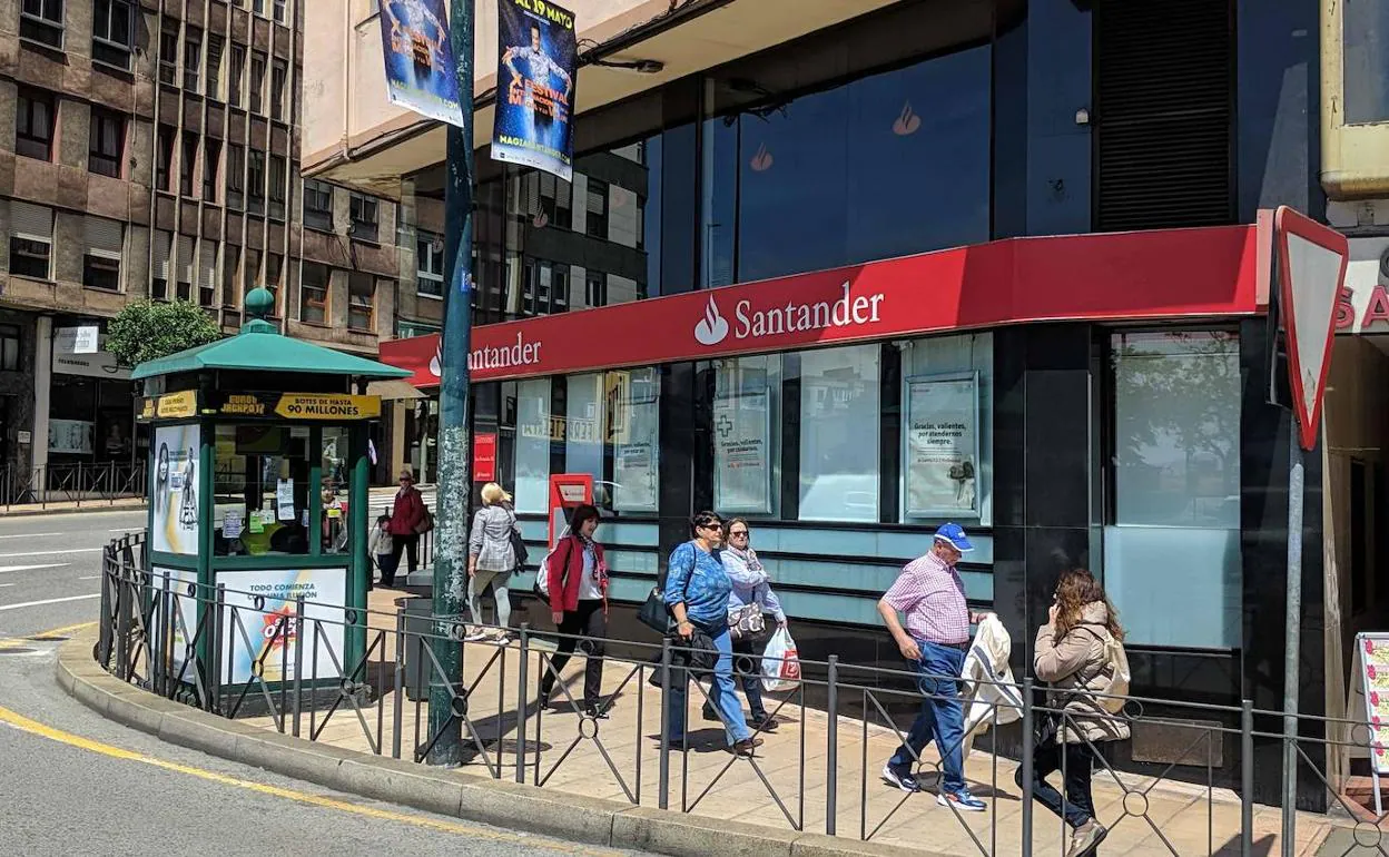 Varias personas pasan por delante de una sucursal del Banco Santander.