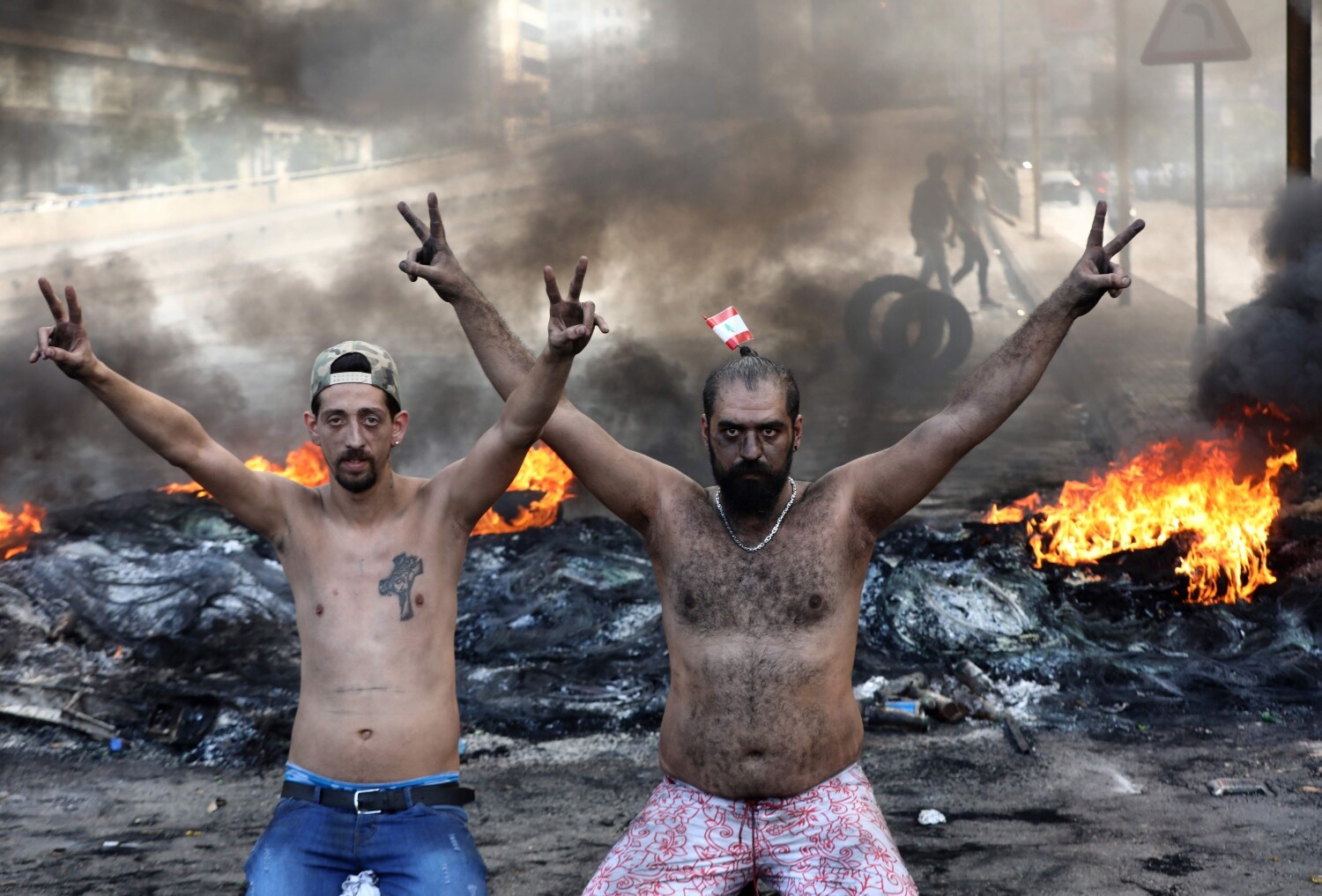 Manifestantes libaneses hacen gestos mientras los neumáticos se queman durante una protesta contra las condiciones económicas nefastas en la zona industrial de Dora, en las afueras del norte de Beirut.
