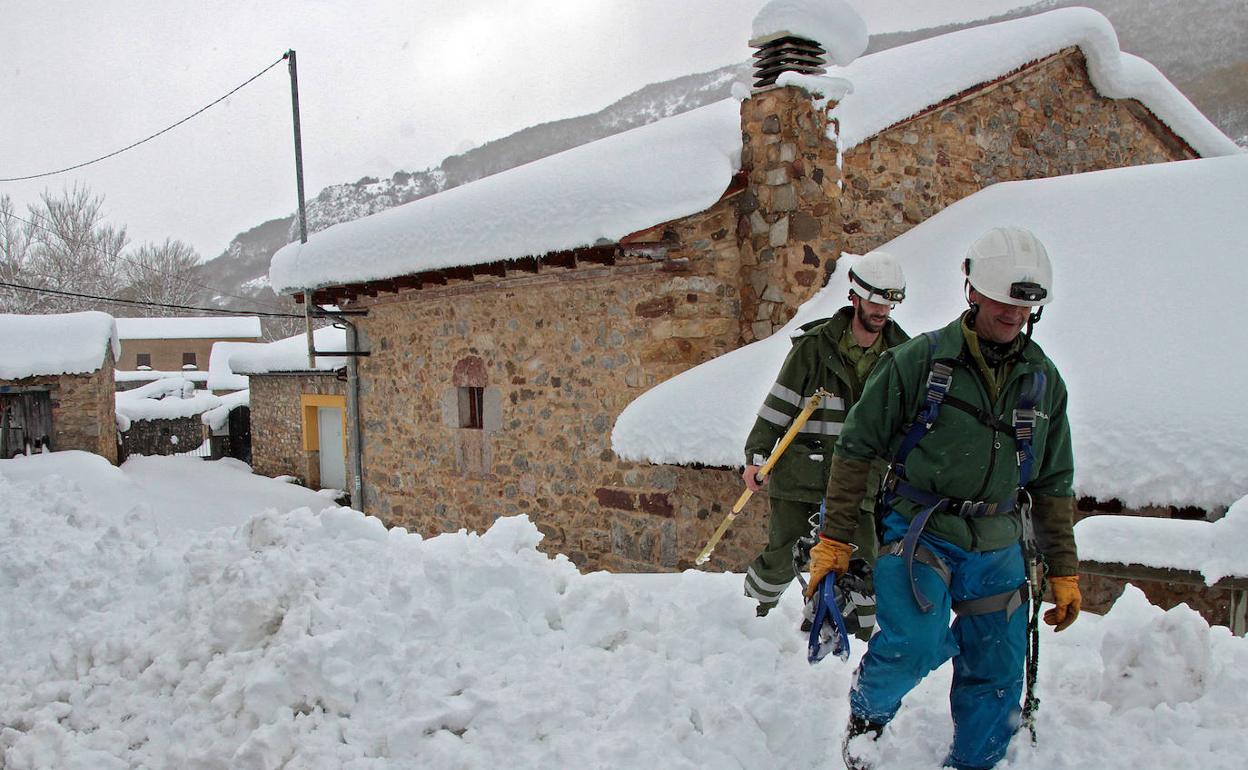 Dos operarios de Iberdrola intentan reparar las líneas eléctricas caídas en los pueblos del municipio de Cármenes.