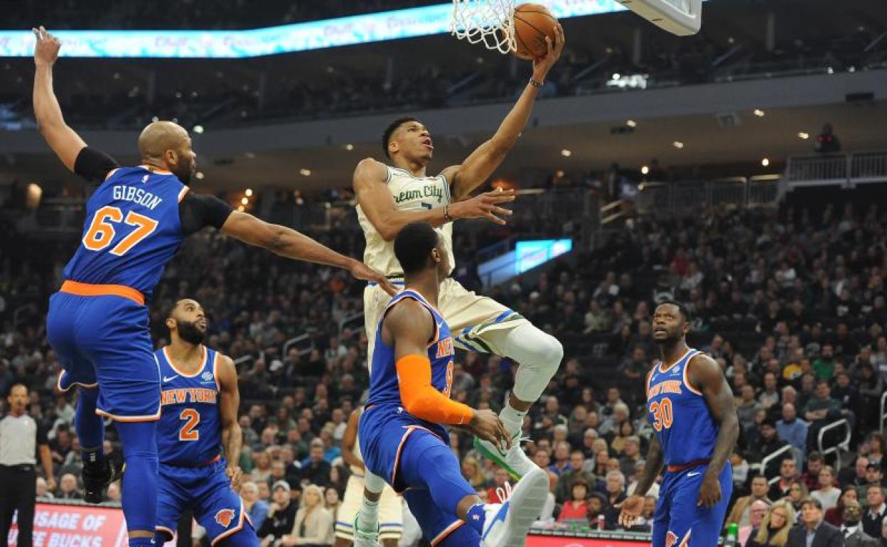 Giannis Antetokounmpo entra a canasta rodeado de defensores. 