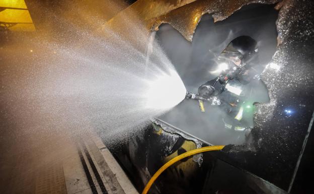 Galería. Imagen de un bombero apagando un incendio en un tren de Feve. 