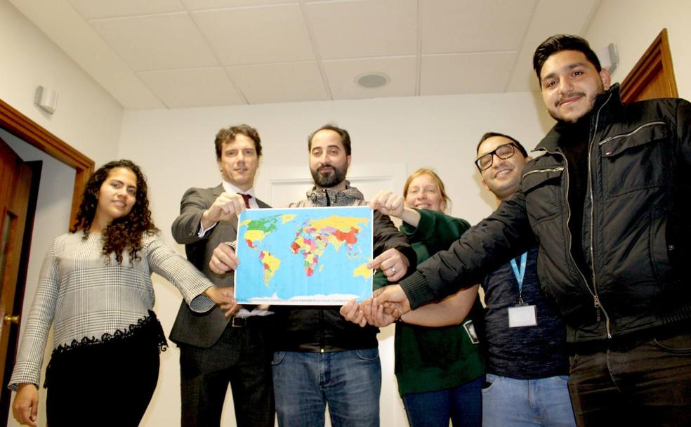 Refugiados, educadores sociales y el director gerente del Hospital sostienen el mapa del mundo. 