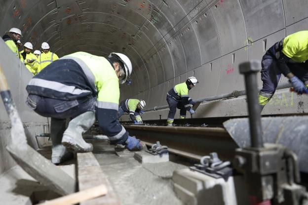 Operarios de FCC, extendiendo la losa de hormigón que fija las vías en el interior de los macrotúneles de la variante. A la derecha, simulación de una evacuación de viajeros. 