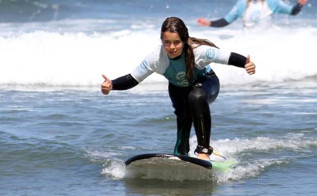 Imagen principal - María, sobre su tabla de surf, en San Juan de la Arena, Asturias.