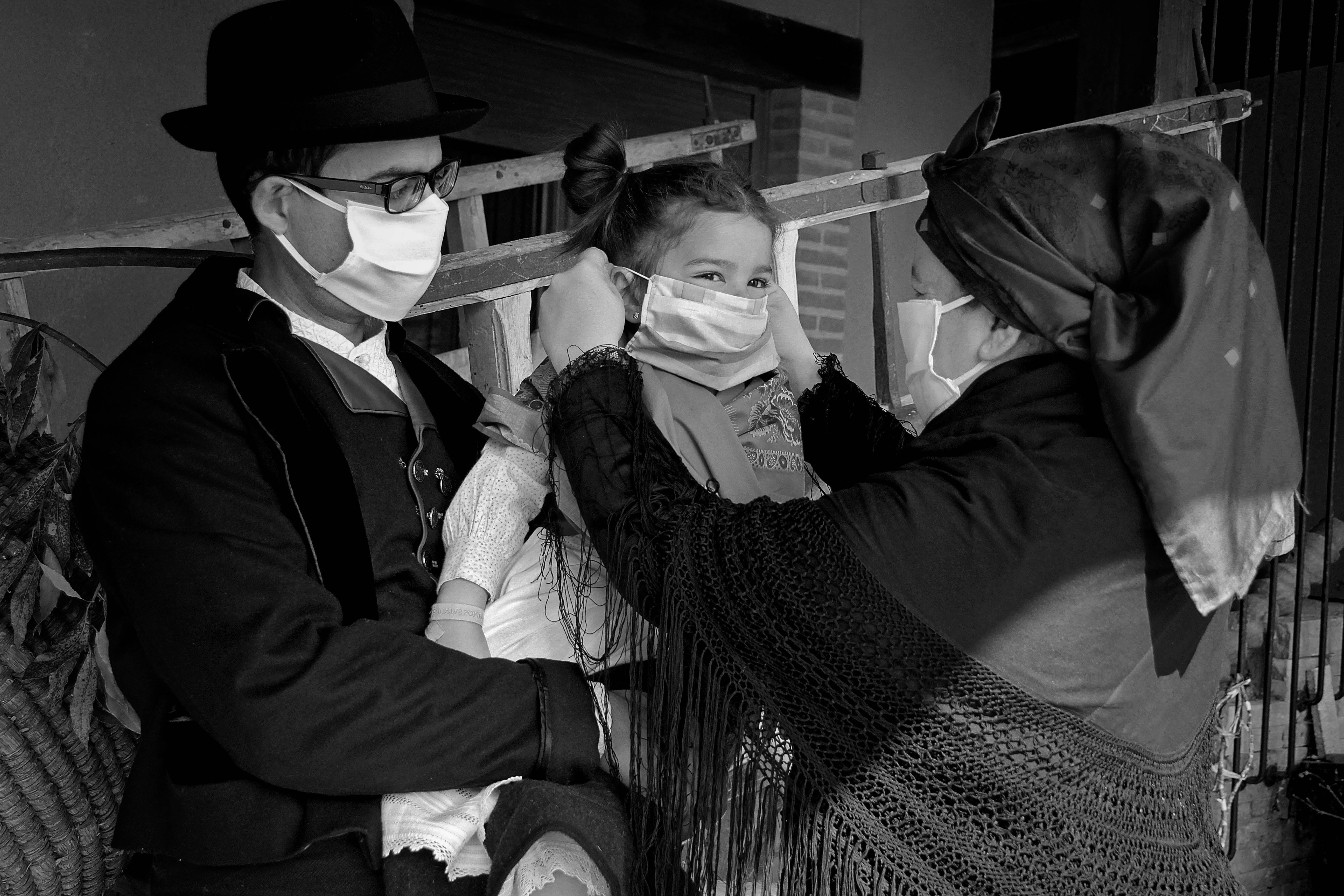 Un matrimonio y su hija, vestidos con indumentaria tradicional leonesa, se protegen contra la infección del coronavirus en Carrizo.