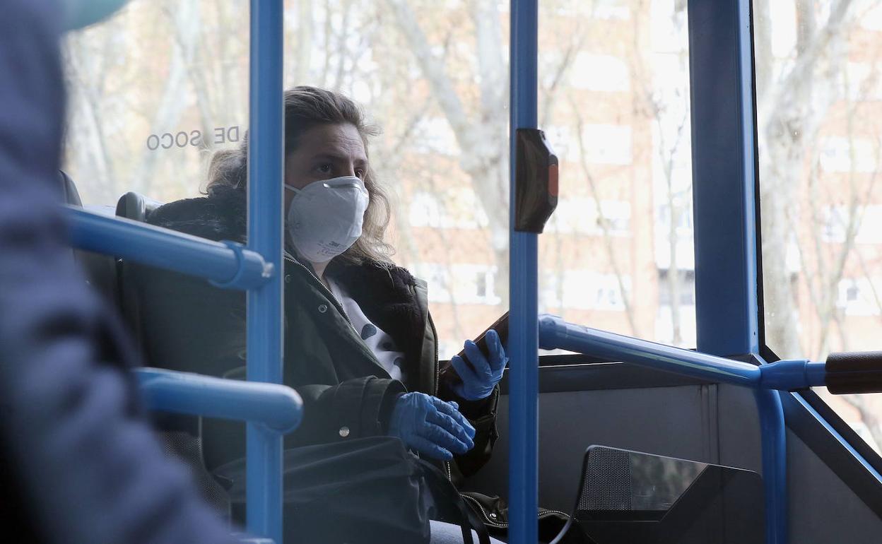 Una mujer viaja en autobús con mascarilla.