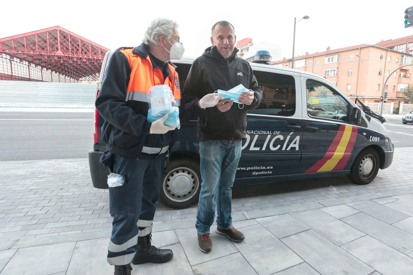 Miembros de Policía Local, Policía Nacional y Protección Civil de León, reparten mascarillas a usuarios del transporte público.