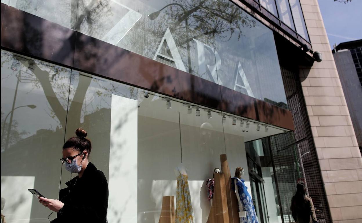 Una mujer con mascarilla pasa por delante de una tienda de Zara cerrada.