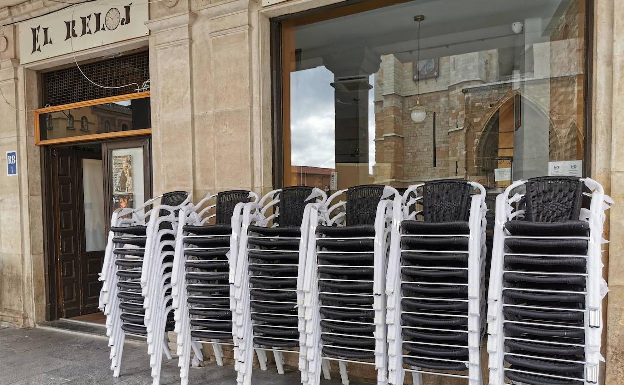 Las sillas de una terraza se amontonan esperando al lunes en León. 