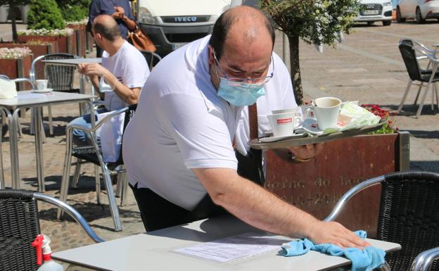 Un camarero de un bar de la Plaza de San Marcelo se afana en limpiar una mesa de su terraza. 