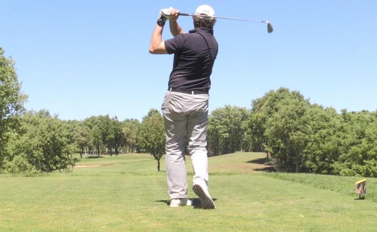 Un deportista muestra su swing con el palo de golf.