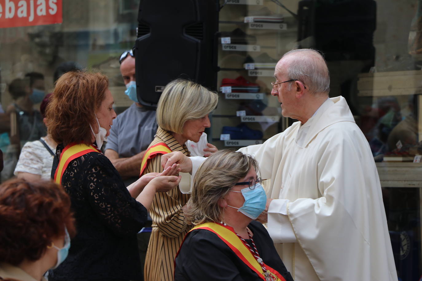 Unas mujeres reciben la comunión mientras portan mascarillas.