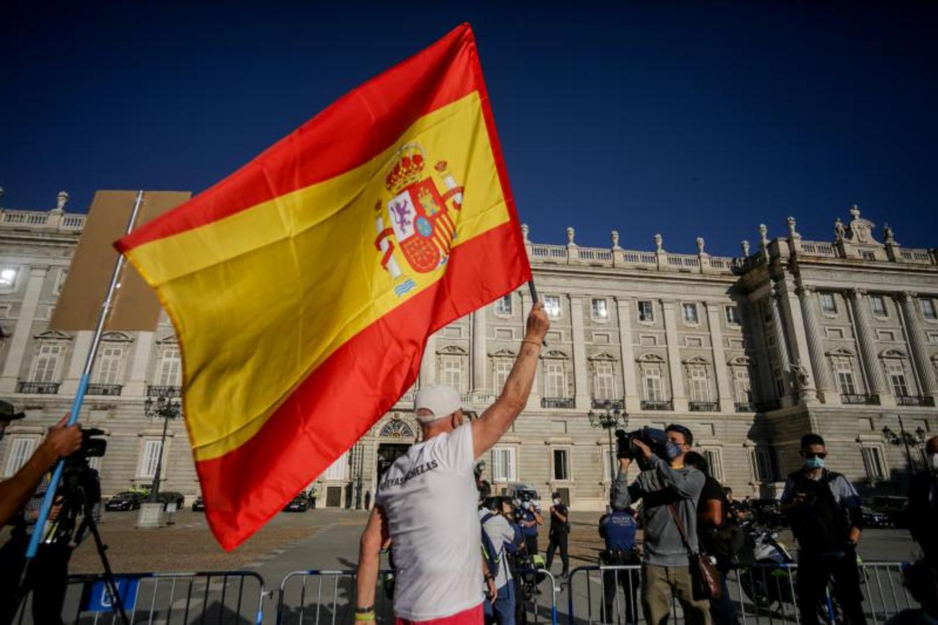 Un hombre ondea una bandera de España en el exterior del Palacio Real