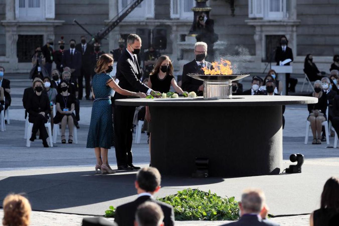 El rey Felipe VI, la Princesa de Asturias, la jefa del servicio de Urgencias del Hospital Vall d'Hebron, Aroa López (i), y Hernando Calleja (d), hermano del periodista José María Calleja, fallecido durante la pandemia, realizan la ofrenda floral