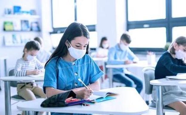 Una alumna escribe en clase durante la pandemia. 