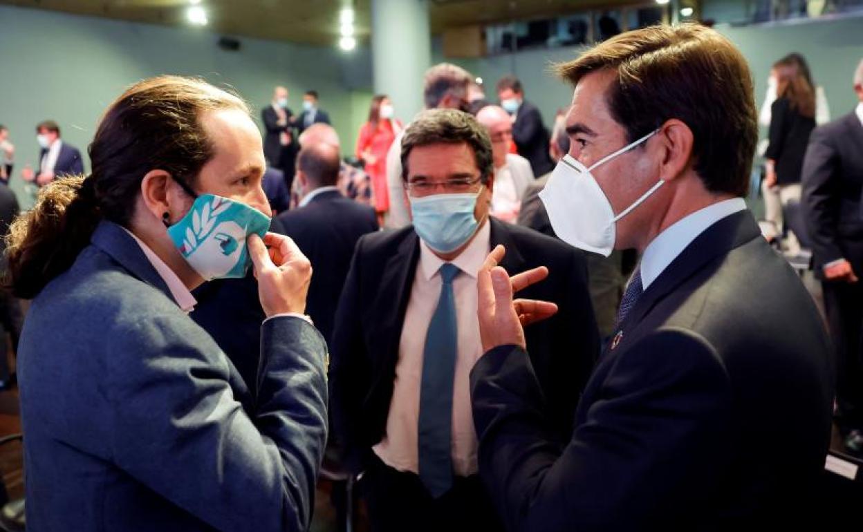 El vicepresidente del Gobierno, Pablo Iglesias (i) conversa con el presidente del BBVA, Carlos Torres (i) junto con el ministro de Seguridad Social, José María Escrivá (c).