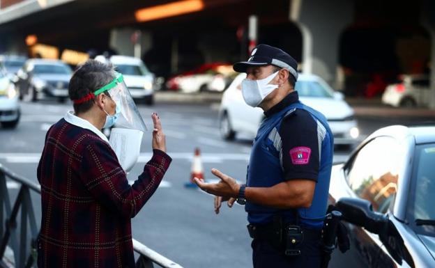 Un policía local habla con una mujer en Vallecas 