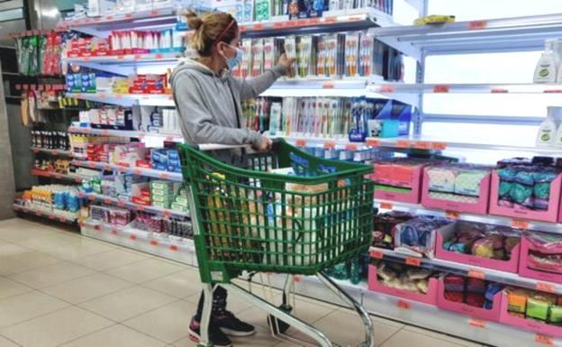 Una mujer compra en un supermercado con la mascarilla.