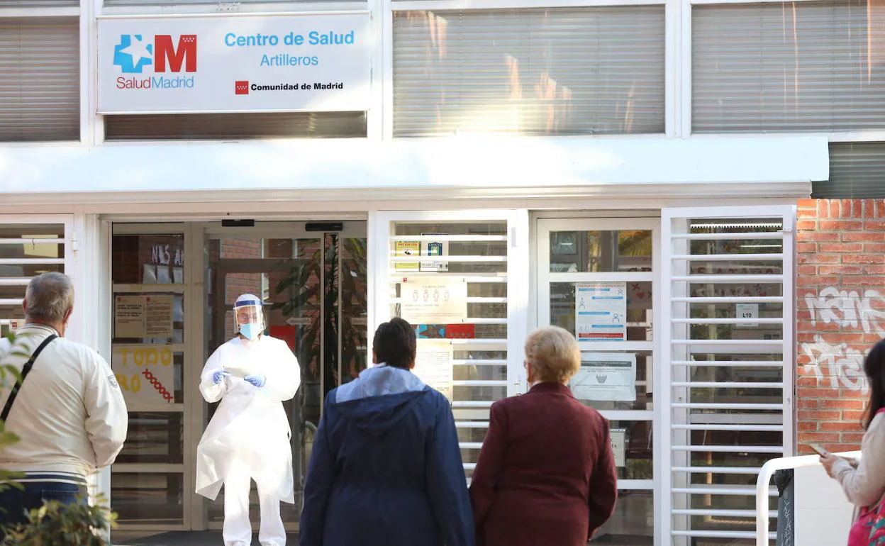 Una sanitaria sale a atender a las numerosas personas que hacen cola en un centro de salud de Madrid