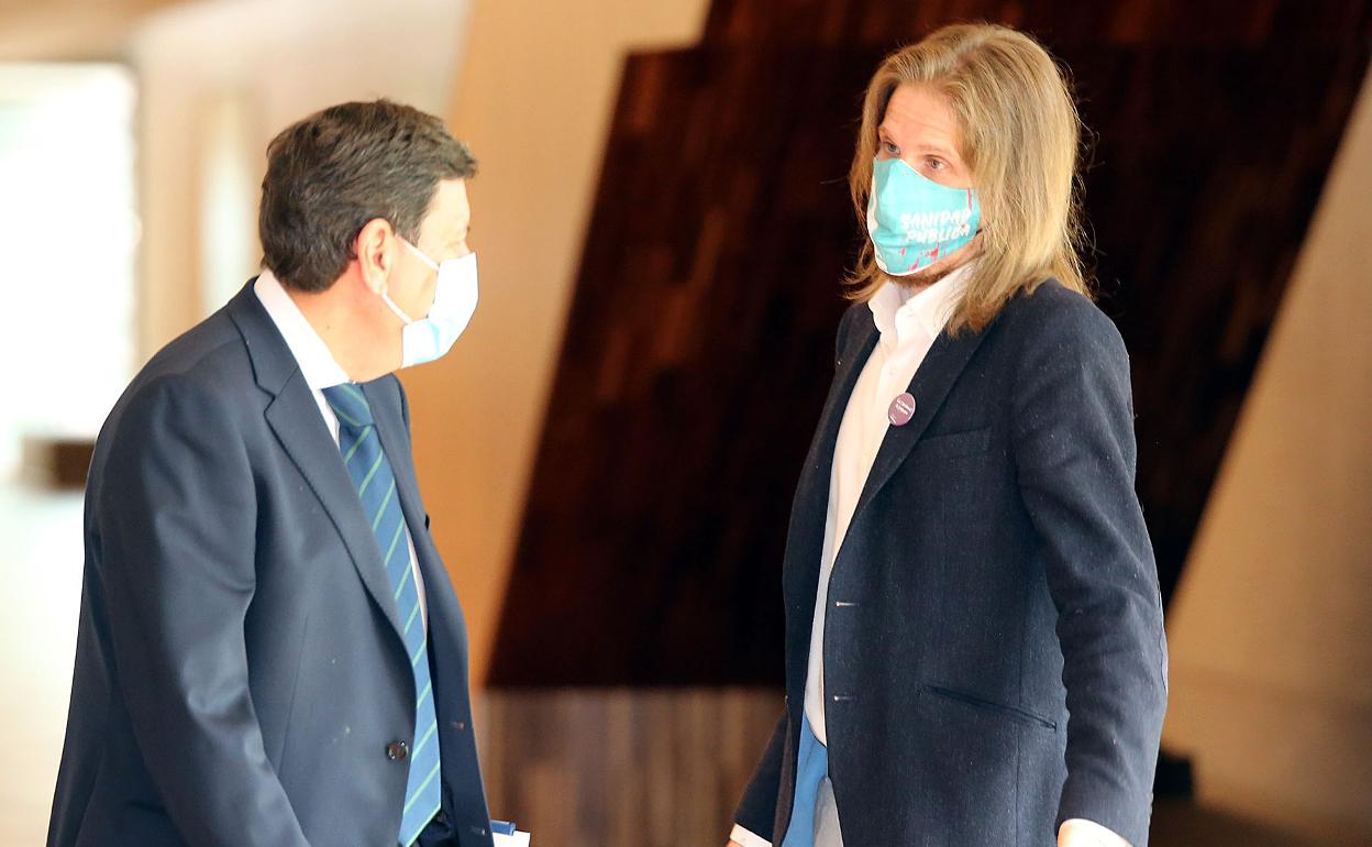 Pablo Fernández, portavoz en las Cortes de Podemos, conversa con el consejero de Hacienda, Carlos Fernández Carriedo.