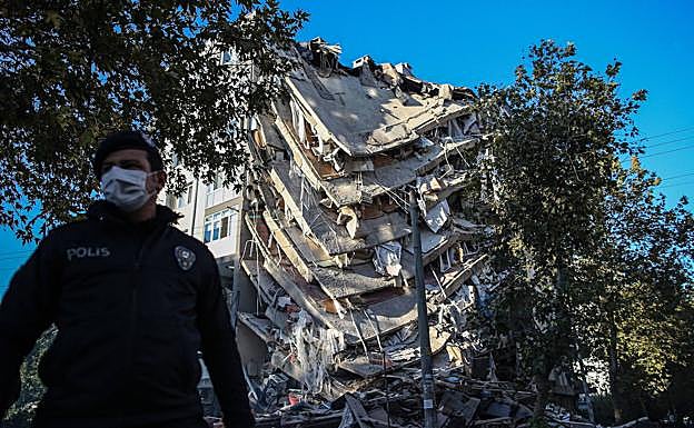 Un policía acordona la zona junto a un edificio derrumbado.