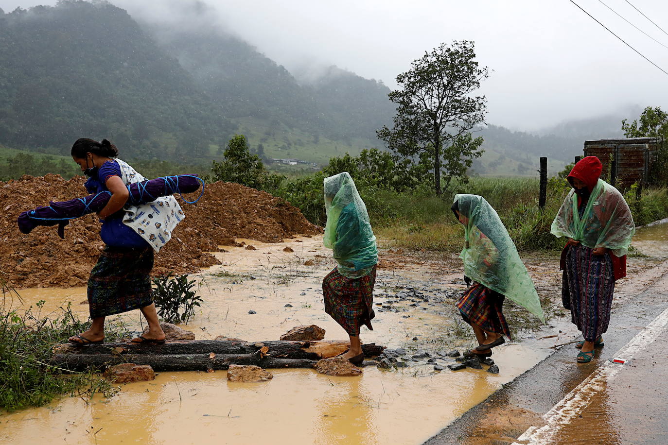 Mujeres caminan en una zona afectada por un deslizamiento de tierra tras el paso de la tormenta Eta, en Purul.