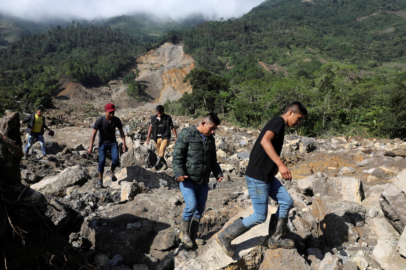 Los residentes caminan por un área afectada por un deslizamiento de tierra, causado por las fuertes lluvias traídas por la tormenta Eta, mientras continúa la búsqueda de víctimas en el pueblo enterrado de Queja.