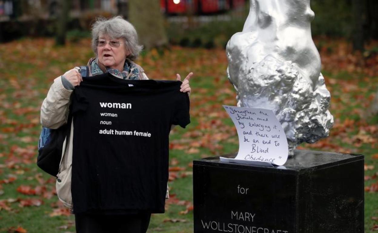 Una mujer sostiene una camiseta junto a la estatua de Mary Wollstonecraft 