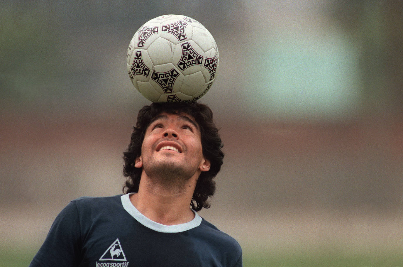 En esta imagen de archivo tomada el 22 de mayo de 1986, Maradona, balancea una pelota de fútbol en su cabeza mientras camina fuera del campo de práctica después de la sesión de práctica de la selección nacional en la Ciudad de México.