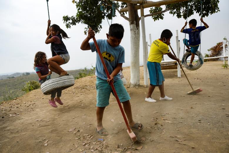 Ecuador | Niños limpian el patio de recreo durante un receso de clases con Denisse Toala (no en la foto), una estudiante de 16 años, que enseña a niños en una escuela improvisada que instaló debajo de un árbol porque no pudieron asistir a clases virtuales. en el barrio popular Realidad de Dios durante el brote del coronavirus en Guayaquil.