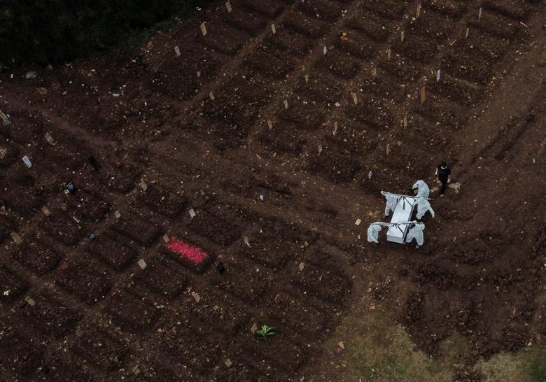 Trabajadores municipales con equipo de protección personal (EPP) llevan el ataúd de una víctima del coronavirus en un área de entierro proporcionada por el gobierno para las víctimas del coronavirus en el complejo del cementerio Srengseng Sawah, en Yakarta, Indonesia.