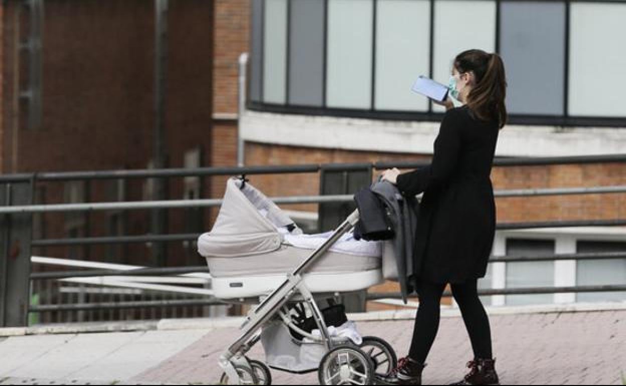 Una mujer pasea con su hijo por las calles de León.