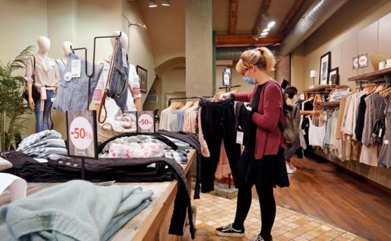 Una mujer compra en una tienda de ropa. 