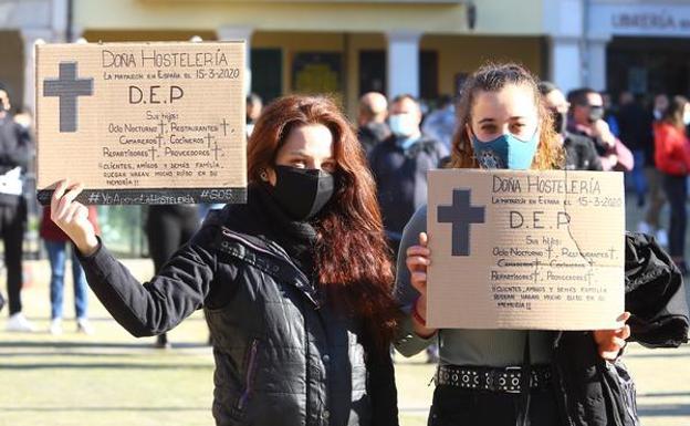 Dos hosteleras muestras carteles anunciando la muerte del sector.