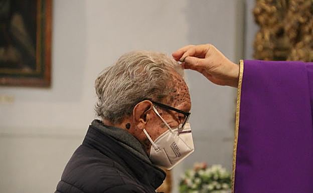 El párroco de la iglesia de Santa Marina deja caer la ceniza sobre la cabeza de un fiel.