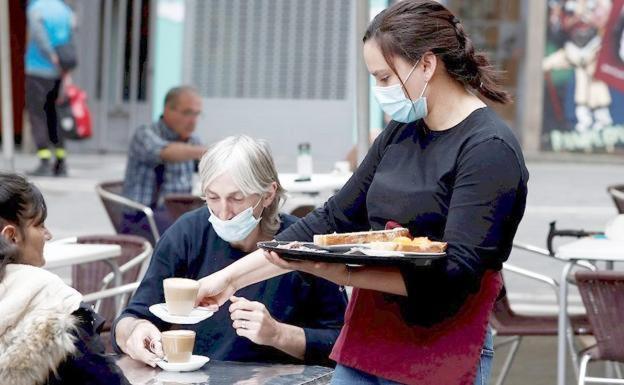 Una camarera sirve en la terraza de una cafetería. 