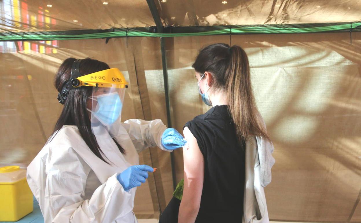 Una enfermera inocula la primera dosis de la vacuna de AstraZeneca a una estudiante de enfermería en el Palacio de Exposiciones de León.