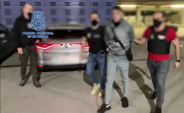 El detenido, custodiado por dos agentes de policía. 